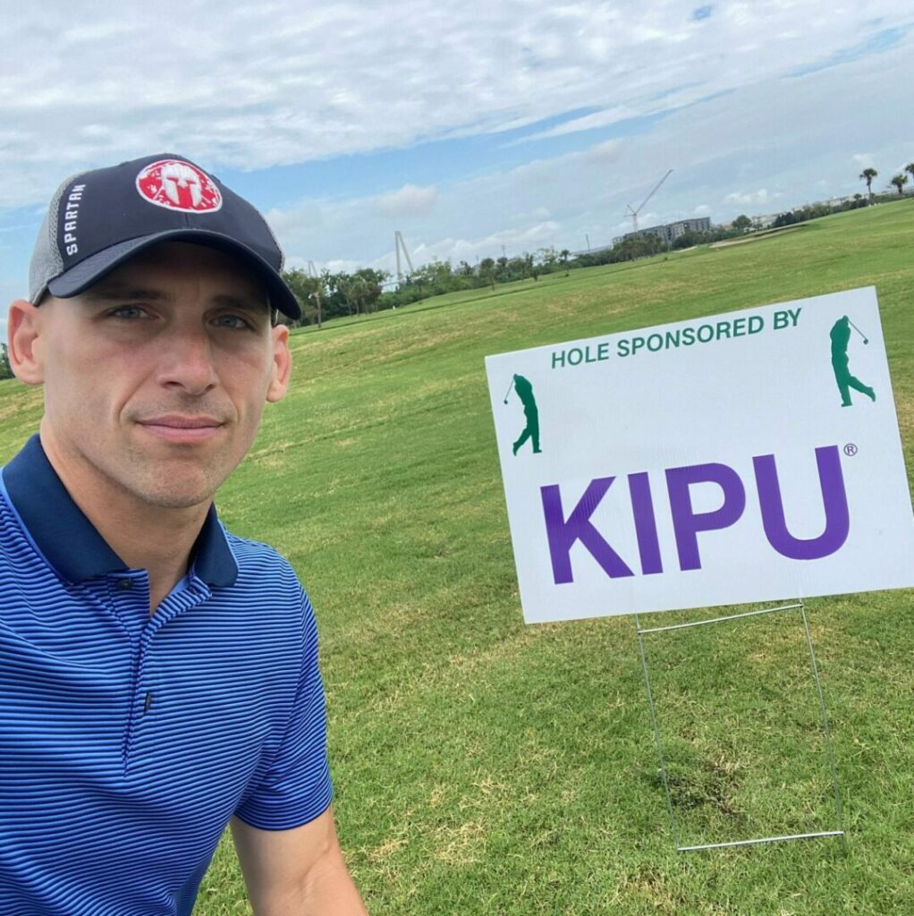 a man on a golf course and a sign that says Hole sponsored by KIPU